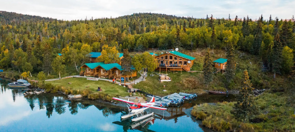 River lodge on the bank with boats and a floating plane
